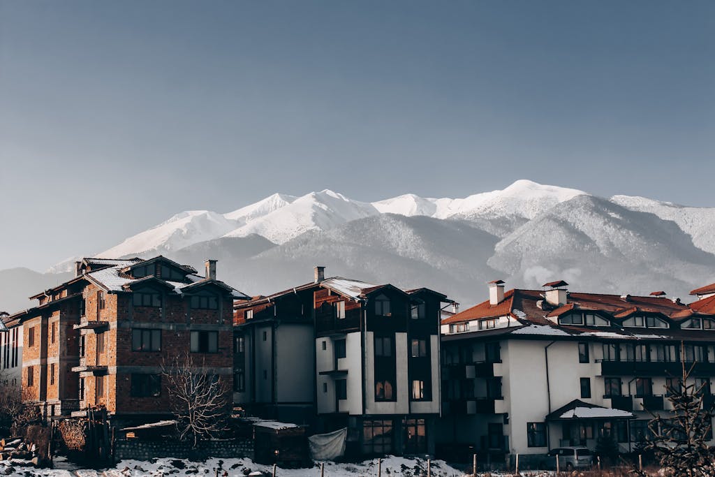 Snow-covered buildings in Bansko with majestic mountain backdrop, perfect for winter travel inspiration.